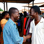 **

"A friendly expat shaking hands with a Zambian local in a bustling Lusaka market. The expat is dressed respectfully, and the market is full of colorful fabrics, fresh produce, and local crafts. Focus on conveying a sense of warmth, cultural exchange, and the beginning of a new life in Zambia."

**